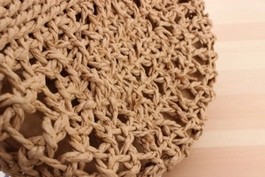 Close-up of handmade hollow woven shoulder bag with natural straw texture and brown lining