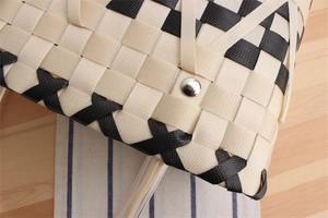 Macro view of woven checkered handbag featuring silver metal rivets and plastic texture