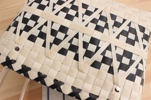 Close-up of woven checkered handbag featuring metal rivets and detailed texture