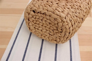 Close-up of the reinforced base showing tight hand-woven straw texture on a beach bag