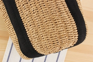 Dettaglio ravvicinato della borsa di paglia con cinghie in tessuto nero in stile estivo