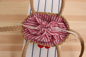 Detailed top view of a woven straw tote bag with red and white striped drawstring lining