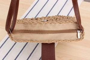 Detail of hand-woven straw bag featuring a metal zipper closure and magnetic buckle snap