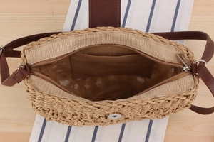Detail view showing the spacious interior and inner pocket of a handmade straw bag