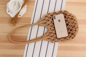 Detail of khaki crochet tote showing phone storage capacity on a rustic wooden table