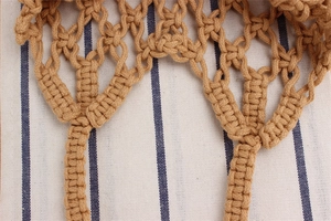 Macro detail of hand-woven cotton rope mesh shoulder bag with sturdy hollow texture