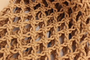 Close-up of hand-woven mesh tote bag featuring a blue and white striped fabric lining