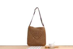 Dettaglio di una borsa in paglia intrecciata marrone scuro con motivi traforati triangolari