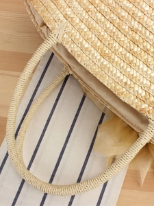Straw beach bag with silk ribbon detail and woven handles for summer vacation