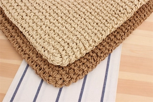 Dettaglio ravvicinato della trama intrecciata di tovagliette in rafia beige e marrone