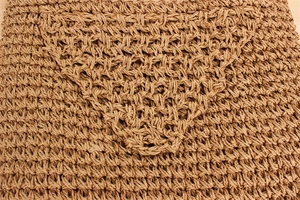 Dettaglio macro della trama intrecciata a mano in paglia naturale e fibre della borsa