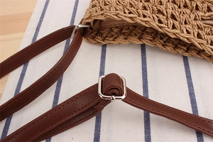 Dettaglio della borsa a tracolla in paglia intrecciata con cinturino in pelle marrone