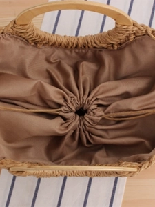 Handwoven straw tote bag with round wooden handles and secure drawstring fabric lining