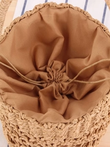 Handwoven straw bucket bag featuring a secure drawstring lining for beach and vacation use