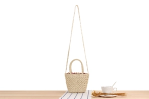 Détail d'un sac en paille tressé avec doublure à carreaux rouges et blancs sur bois