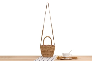 Détail du sac seau en paille tissée avec doublure à carreaux rouges et bandoulière