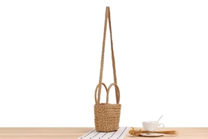Détail d'un sac seau en paille tissé main avec doublure à carreaux rouges sur bois