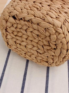 Handwoven straw beach bag featuring detailed texture on a white blue striped background