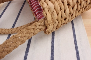 Gros plan détaillé du sac en paille tissée avec doublure en toile à rayures rouges et blanches