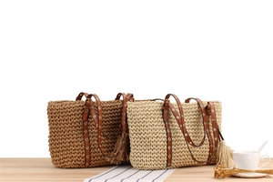 Detail of hand-woven tote bags with leather straps and oversized fringe tassels on a table