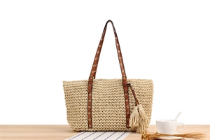 Detailed texture of handwoven paper rope beach bag with brown leather strap and tassel