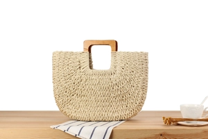 Gros plan du sac cabas tissé crème avec poignées carrées en bois sur table rustique