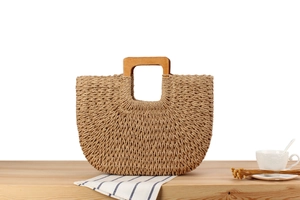 Détail d'un sac de plage tressé à la main avec poignées en bois sur table rustique
