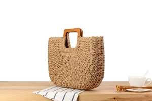 Gros plan d'un sac de plage tressé main avec poignées en bois sur table en bois