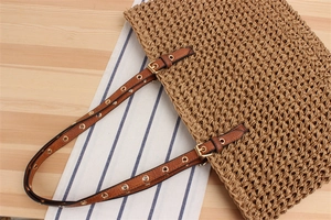 Macro detail of handwoven paper rope bag featuring brown leather strap and metal eyelets