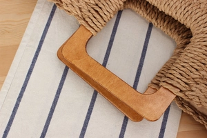 Gros plan détaillé du sac en paille tressée avec une poignée rectangulaire en bois poli chic