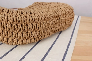 Gros plan sur la texture tissée épaisse et la fixation de l'anse en cuir du sac en paille