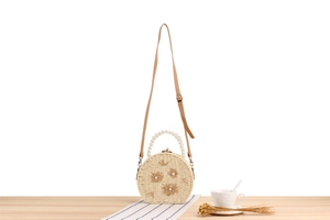 Détails du sac rond en paille avec broderie florale, anse en perles et bandoulière