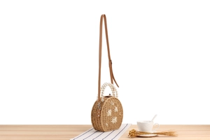 Détail du sac rond en paille avec broderies florales, perles et bandoulière cuir