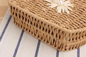 Détail du sac tissé main avec pétale de fleur en paille et centre de perles blanc