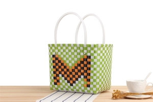 Detail of woven checkered basket bag in green and white featuring a large orange letter M