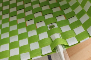 Detail of green and white woven shopping bag with clear handle and metal rivet