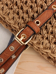 Brown leather shoulder strap with gold buckle and eyelets on a woven beach bag