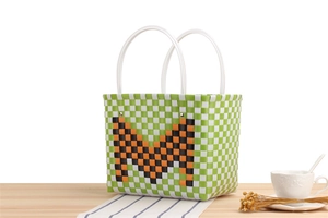 Detail of woven checkered basket bag with large M letter on a cozy wooden table
