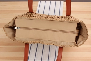 Detailed interior of woven straw tote bag featuring fabric lining and zipper closure