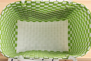 Top-down view of green and white checkered woven basket bag with clear tube handles