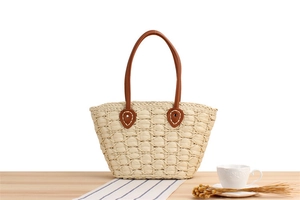 Close-up of hand-woven straw tote with premium leather handles and metal hardware