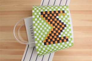 Detail of green checkerboard woven tote bag with transparent handles and geometric pattern