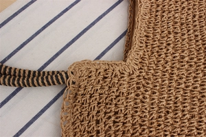 Detailed close-up of handmade woven straw bag with spiral texture handle and natural finish