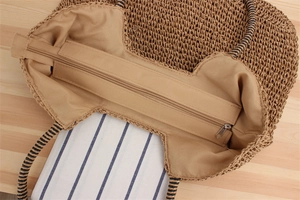 Detail of woven tote bag showing metal zipper closure and striped wrap handle design