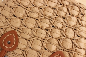 Macro detail of hand-woven straw bag with leather trim, stitching and metal rivet