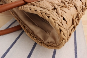 Detail of woven straw bag showing secure stitching and brown leather handle attachment
