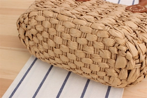 Macro detail of the woven pattern and sturdy faux leather handle on a straw tote bag