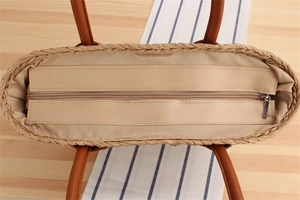 Top view of handmade straw tote bag with zipper closure and brown leather handles