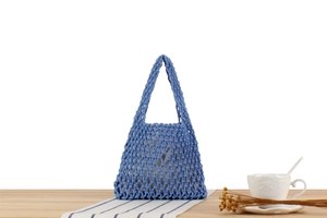 Detailed close-up of blue handmade macramé woven bag on a wooden table with home decor