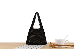 Detail of black handmade crochet tote bag with hollow woven mesh and beige inner lining